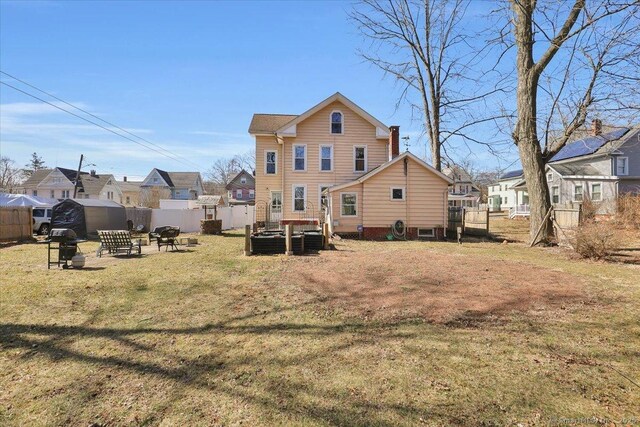 back of house with a residential view, a fire pit, a lawn, and a fenced backyard