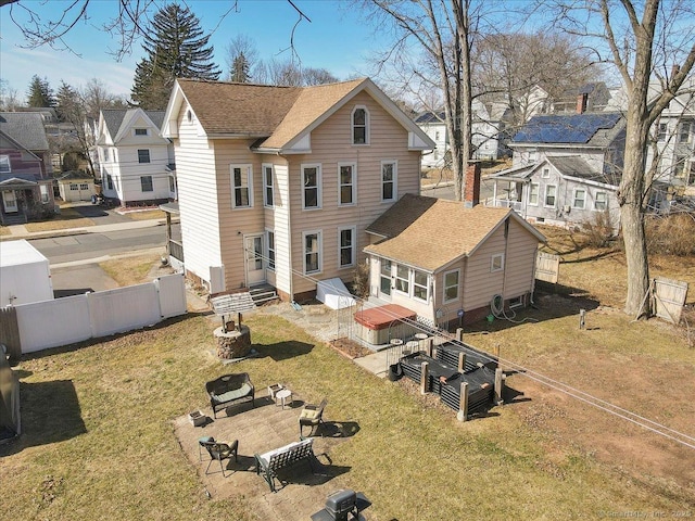 rear view of house with a shingled roof, fence, a residential view, entry steps, and a yard