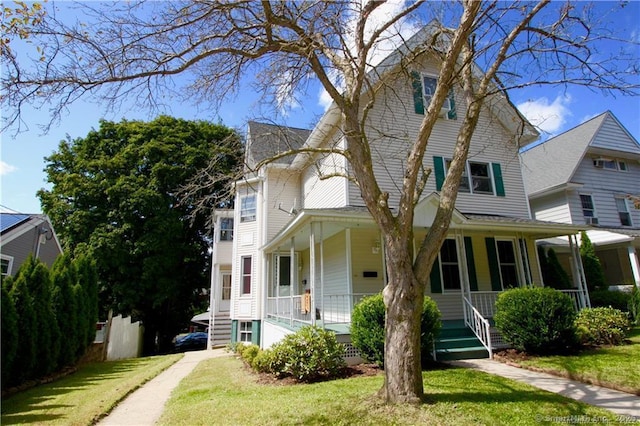 view of front of property featuring a porch, a front yard, and driveway