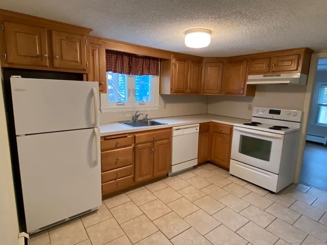 kitchen featuring white appliances, brown cabinetry, light countertops, under cabinet range hood, and a sink