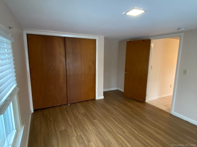 unfurnished bedroom featuring a closet, baseboards, and wood finished floors