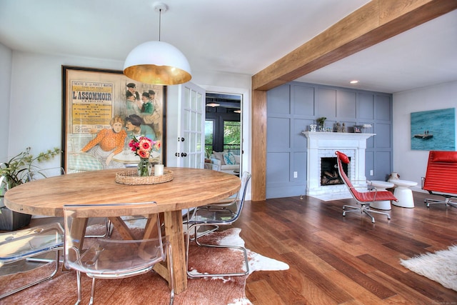 dining room featuring a brick fireplace, beam ceiling, and wood finished floors