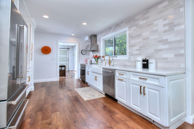 kitchen with dark wood-style floors, light countertops, white cabinetry, high quality appliances, and wall chimney exhaust hood