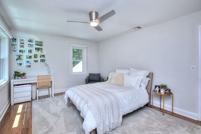 bedroom with light wood-style floors, baseboards, visible vents, and a ceiling fan