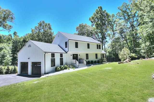 view of front facade featuring aphalt driveway, a chimney, a shingled roof, a front yard, and a garage