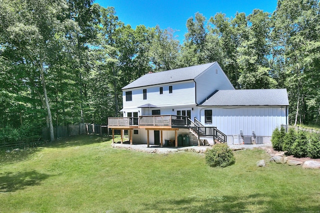 back of property featuring a yard, stairway, a wooden deck, and fence