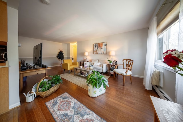 living area with baseboard heating, wood finished floors, and baseboards