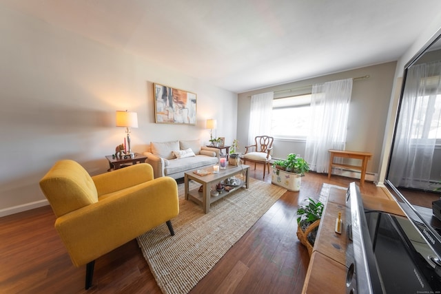 living area featuring a wealth of natural light, baseboards, a baseboard heating unit, and wood finished floors