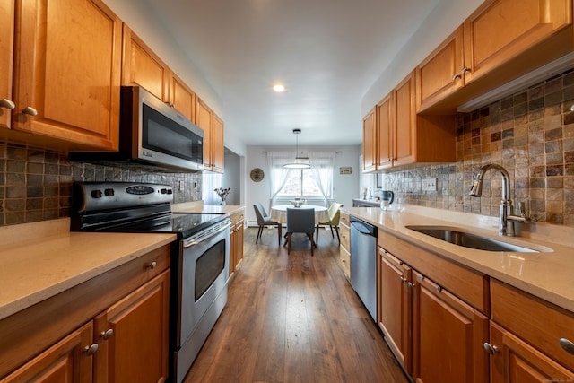 kitchen featuring appliances with stainless steel finishes, brown cabinetry, a sink, and light countertops