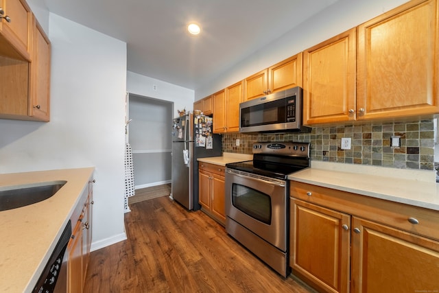 kitchen with light stone counters, dark wood-style flooring, stainless steel appliances, decorative backsplash, and baseboards