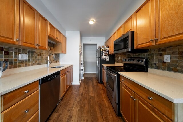 kitchen with stainless steel appliances, brown cabinetry, a sink, and dark wood-type flooring