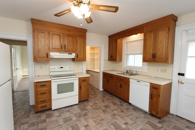 kitchen featuring white appliances, brown cabinetry, light countertops, under cabinet range hood, and a sink