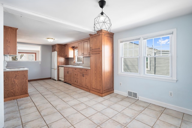 kitchen with visible vents, light countertops, hanging light fixtures, a sink, and white appliances