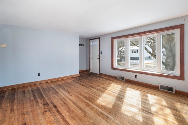 interior space featuring light wood-type flooring, visible vents, and baseboards