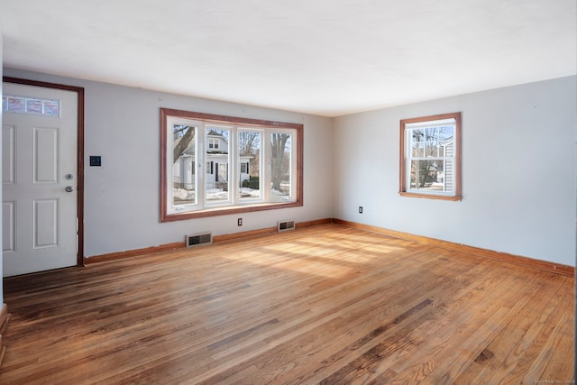 spare room featuring visible vents, baseboards, and wood finished floors