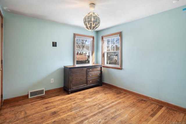 unfurnished room with light wood finished floors, baseboards, visible vents, and a notable chandelier