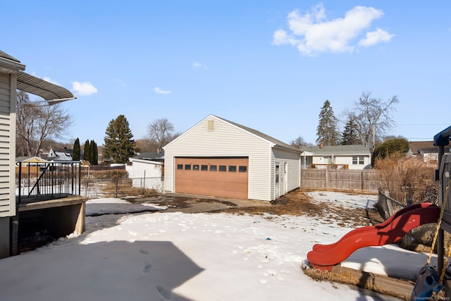 snow covered garage with a garage and fence