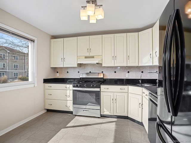 kitchen with freestanding refrigerator, stainless steel gas stove, a sink, under cabinet range hood, and dishwashing machine