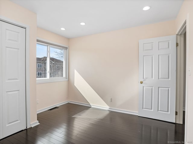 unfurnished room featuring baseboards, visible vents, dark wood-type flooring, and recessed lighting