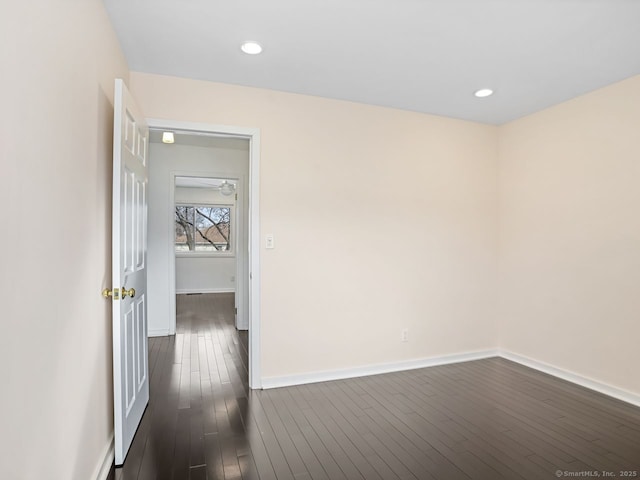 spare room featuring dark wood-type flooring, recessed lighting, and baseboards