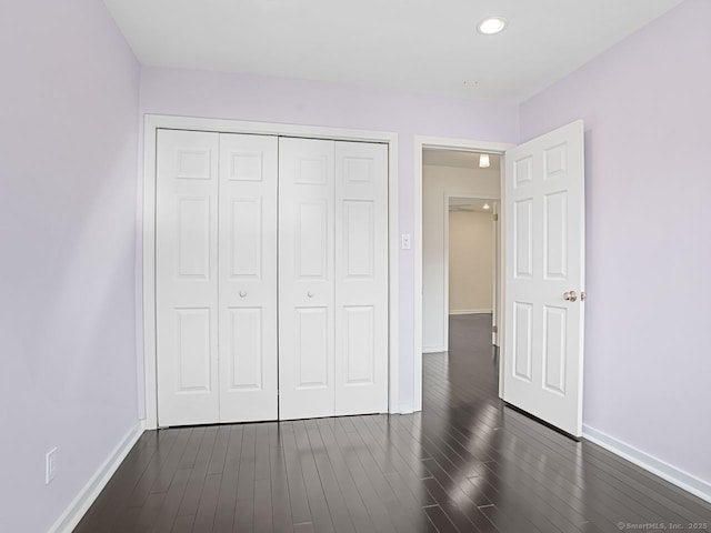 unfurnished bedroom featuring dark wood-style floors, baseboards, a closet, and recessed lighting