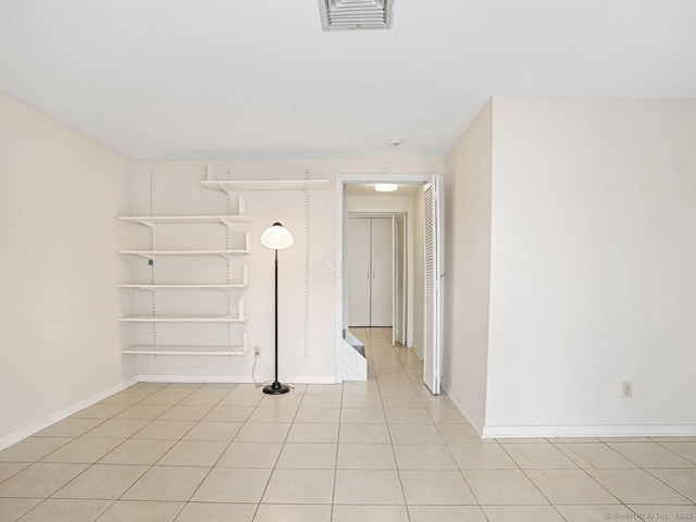 empty room featuring light tile patterned floors, baseboards, and visible vents