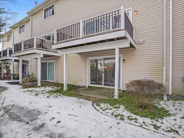 snow covered back of property with a balcony