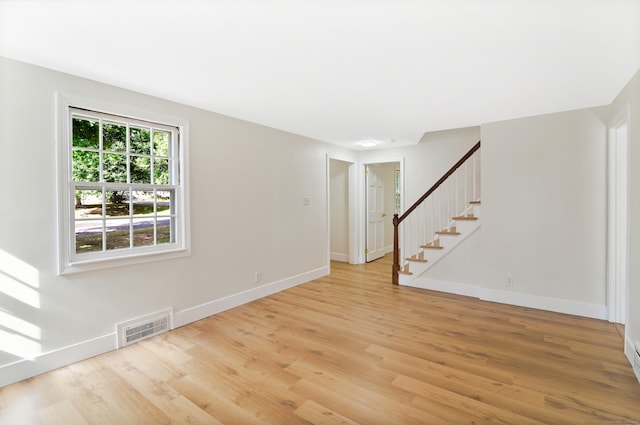 unfurnished room featuring stairway, baseboards, visible vents, and light wood finished floors