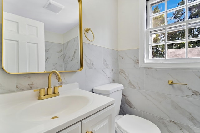 half bathroom featuring tile walls, visible vents, vanity, and toilet