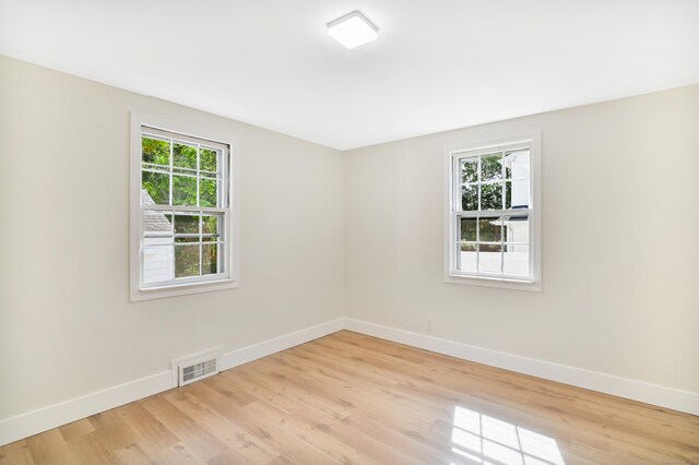 unfurnished room featuring light wood finished floors, visible vents, and baseboards