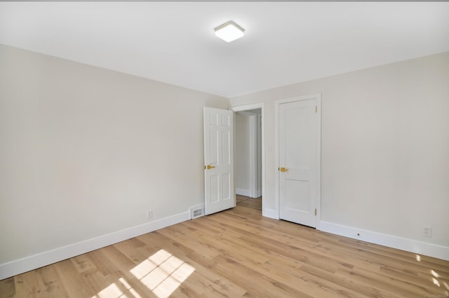 empty room featuring visible vents, light wood-style flooring, and baseboards