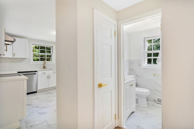 bathroom featuring tile walls, toilet, a wainscoted wall, marble finish floor, and a closet