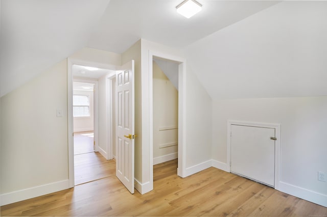 additional living space featuring light wood-type flooring, vaulted ceiling, and baseboards