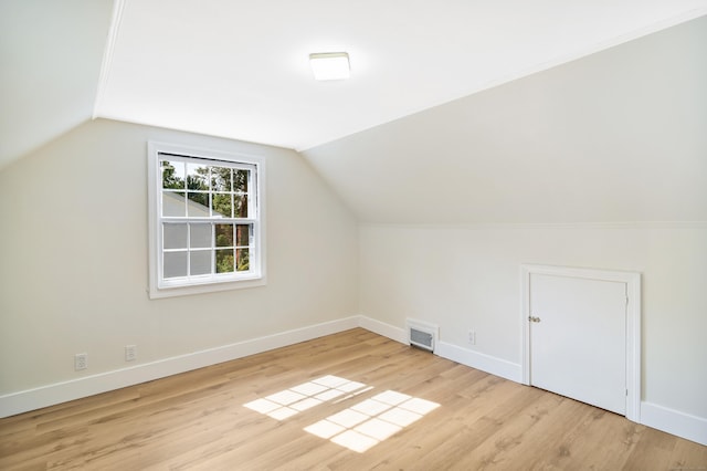 bonus room featuring light wood-type flooring, visible vents, vaulted ceiling, and baseboards