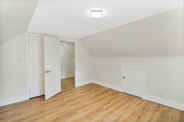 additional living space featuring light wood-type flooring, vaulted ceiling, and baseboards