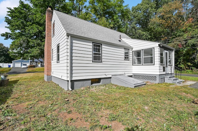 view of front of house with a shingled roof, a chimney, and a front yard