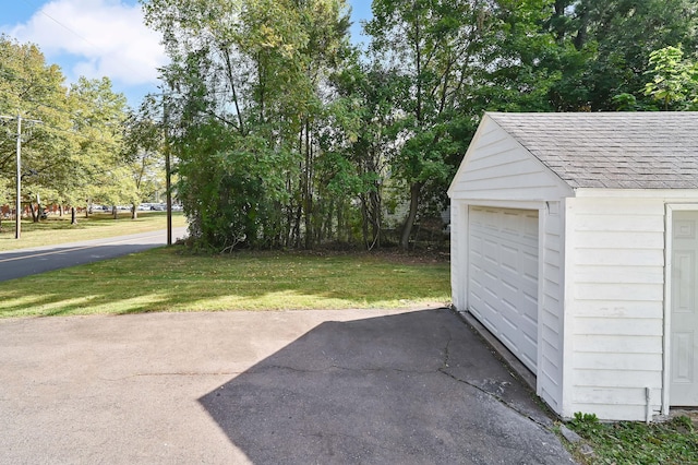 exterior space with a detached garage, aphalt driveway, and an outdoor structure