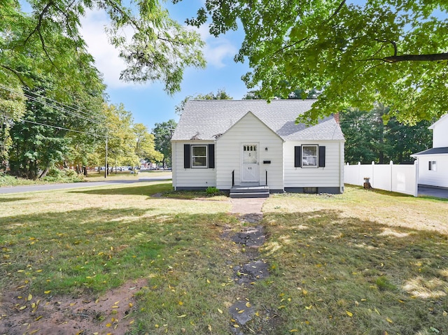 view of front of property featuring roof with shingles, fence, and a front lawn