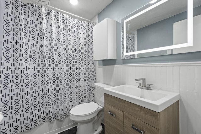 bathroom with wainscoting, vanity, and toilet