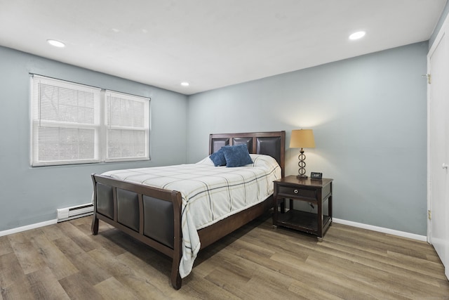 bedroom with a baseboard heating unit, recessed lighting, wood finished floors, and baseboards