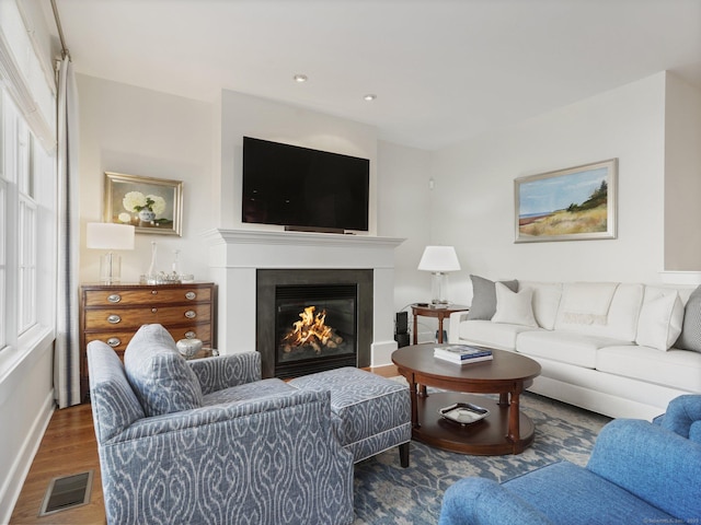 living area with recessed lighting, visible vents, a glass covered fireplace, wood finished floors, and baseboards