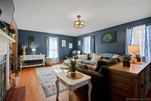 living area with a fireplace with flush hearth, a wealth of natural light, and wood finished floors