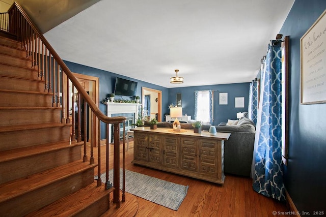 interior space with stairway, wood finished floors, and a tile fireplace