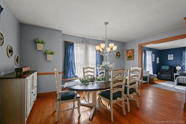 dining room with light wood-style flooring, a chandelier, and baseboards