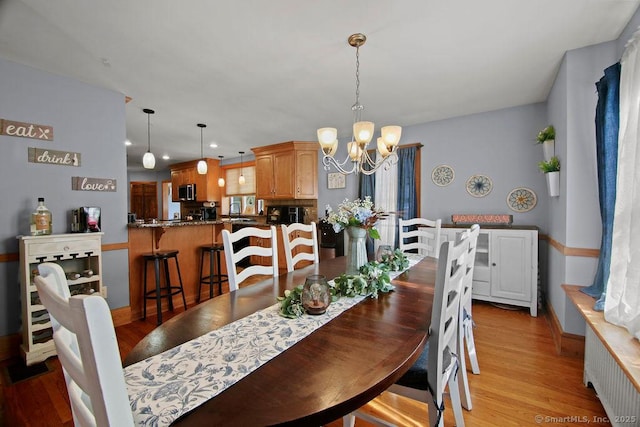 dining room with a chandelier, recessed lighting, and light wood-style floors