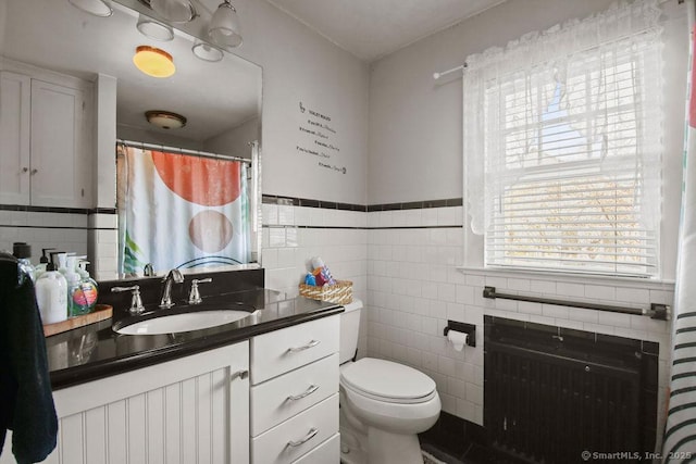 full bathroom with toilet, vanity, tile walls, wainscoting, and radiator