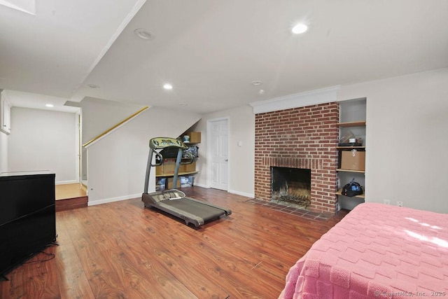 bedroom with recessed lighting, a brick fireplace, baseboards, and wood finished floors