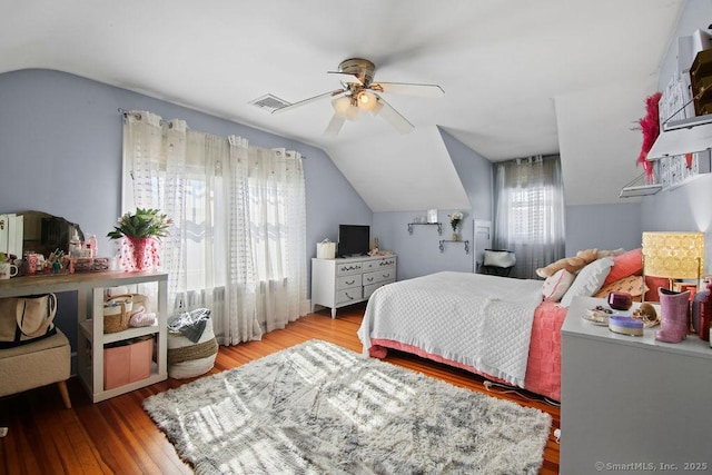 bedroom with a ceiling fan, lofted ceiling, visible vents, and wood finished floors