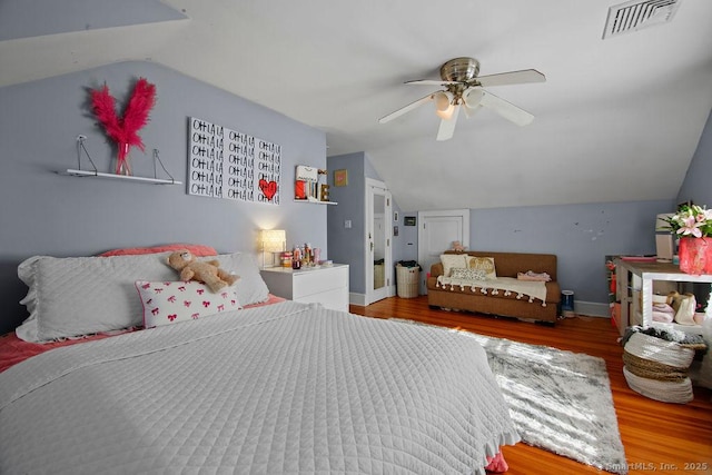 bedroom featuring baseboards, visible vents, vaulted ceiling, and wood finished floors