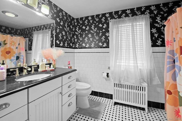 bathroom featuring radiator heating unit, wainscoting, tile walls, and wallpapered walls